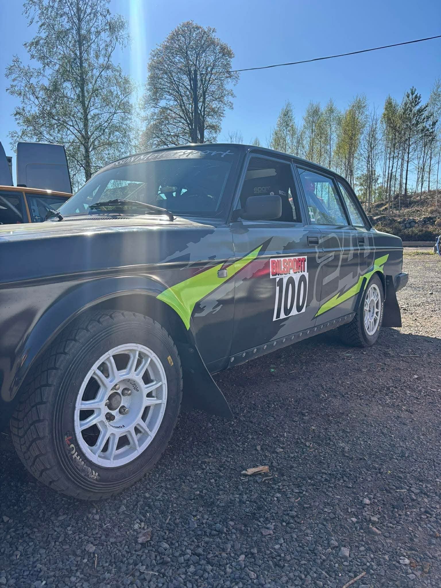 Närbild på grå Volvo 240 rallybil med vita rallyfälgar