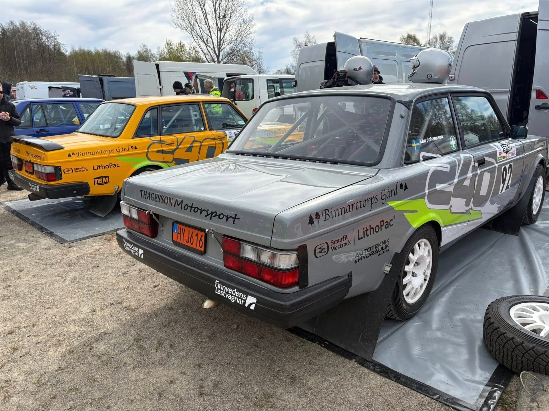 Silver och gul Volvo 240 rallybilar från Thagesson Motorsport i depån med hjälmar på taket
